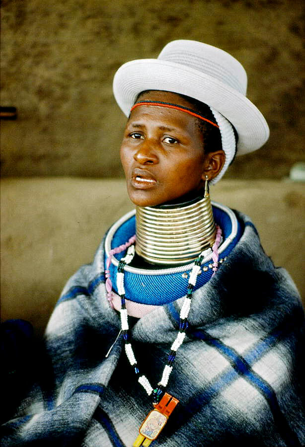 An Ndebele woman traditional neck ring attire and a Western-style hat. Flickr / United Nations Photo